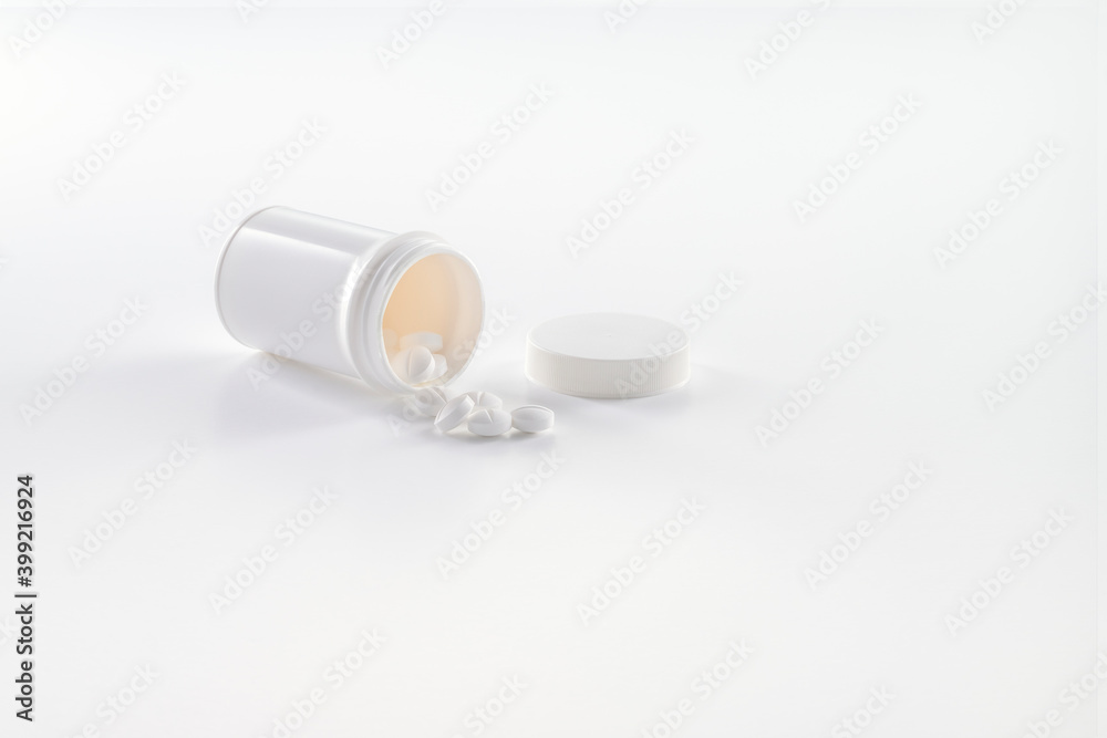 A white open medicine bottle with white pills spilling out of the inside on a white background A white open medicine bottle with white pills spilling out of the inside on a white background