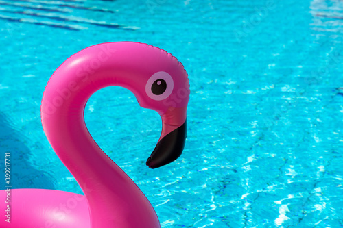 Tropical background. Pink inflatable flamingo in pool water for summer beach background. Minimal summer concept. © Maksym