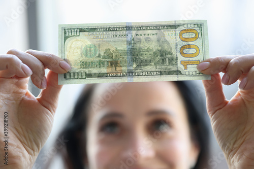 Woman holding dollar bill and looking at it with watermarks closeup photo