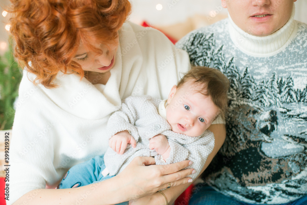 A young family in warm sweaters with a baby daughter in a Christmas bedroom interior decorated with red blankets, pillows, garlands and green pine needles. Family and Children. Christmas mood
A young family in warm sweaters with a baby daughter in a Christmas bedroom interior decorated with red blankets, pillows, garlands and green pine needles. Family and Children. Christmas mood