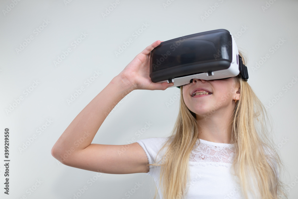 Portrait of little girl in a white t-shirt having fun with virtual reality headset on light background Portrait of little girl in a white t-shirt having fun with virtual reality headset on light background