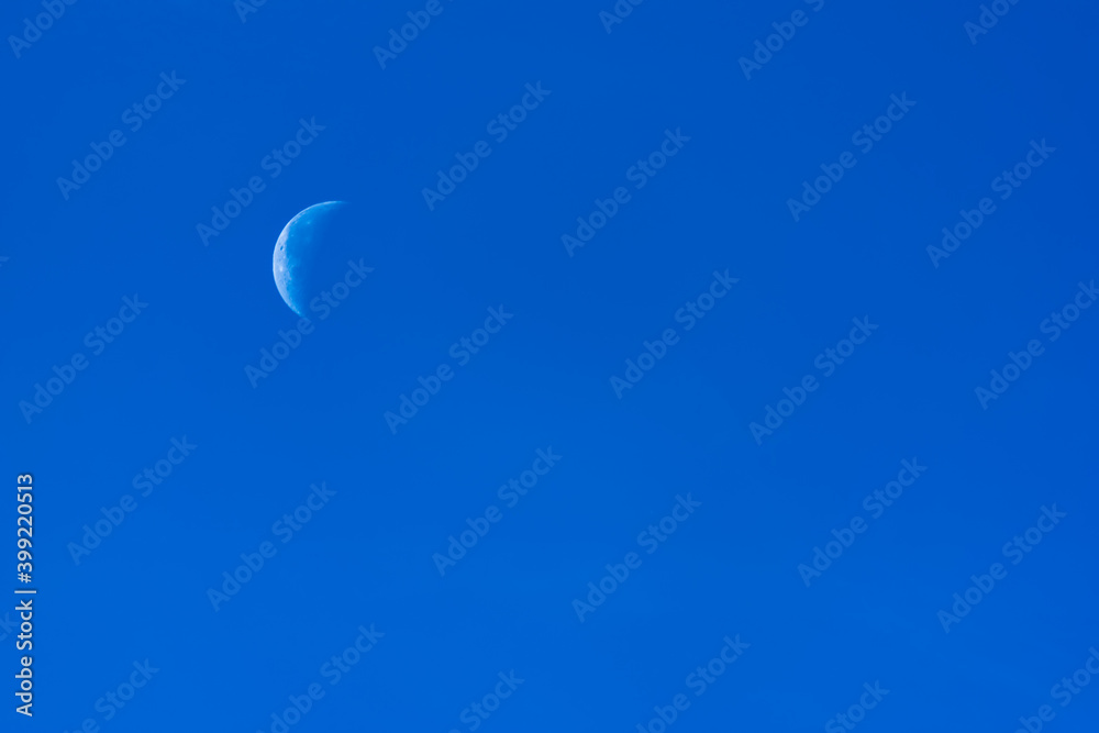 Last quarter moon in the morning against the blue sky.