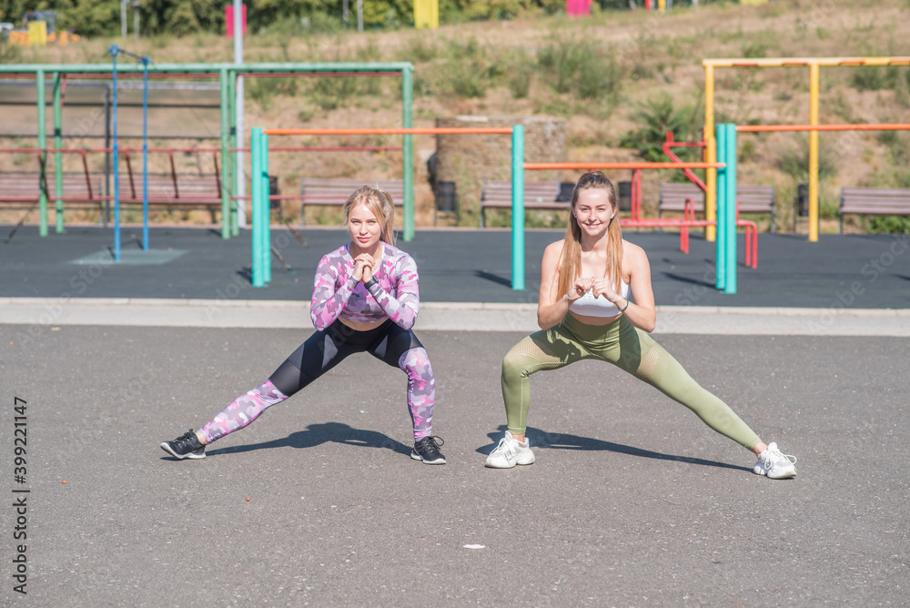 Two beautiful and athletic girls lunges on the playground