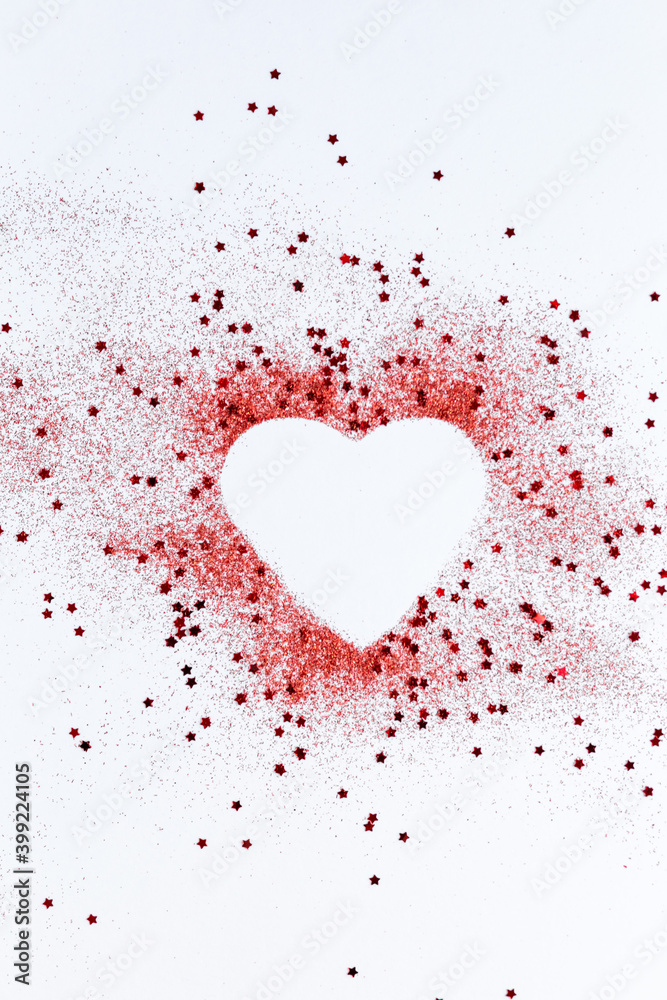 Red confetti glitter in shape of heart on white festive background, copy space, valentines day festive card
