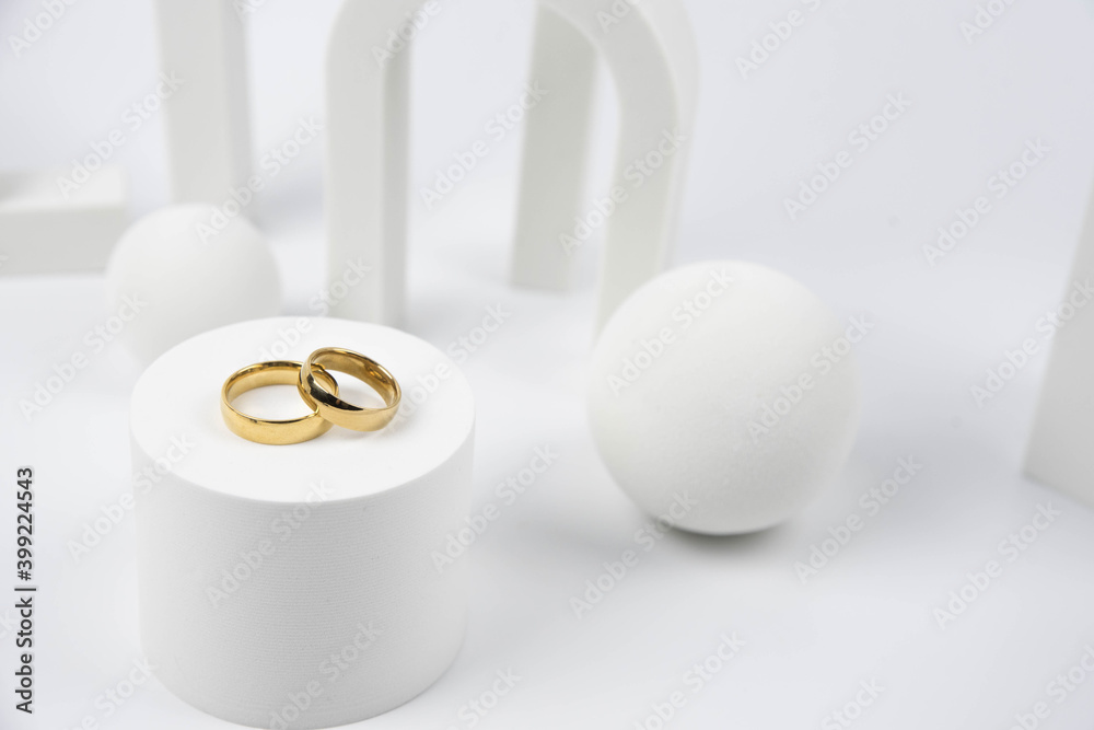 Golden wedding rings on trendy white podium. Aesthetic still life art photography. Golden wedding rings on trendy white podium. Aesthetic still life art photography.