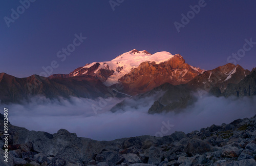 Mountain landscape. Elbrus at sunset. Clouds under the mountain. August