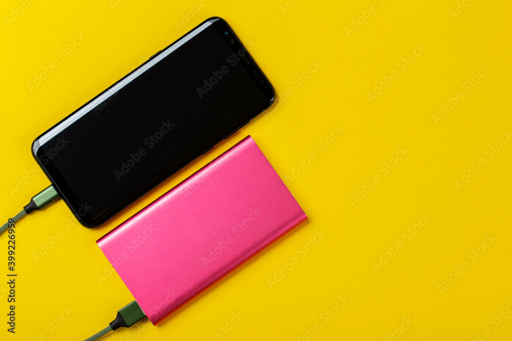 Smartphone Charging with Power Bank on Yelloy Background. Space for text. Smartphone Charging with Power Bank on Yelloy Background. Space for text.