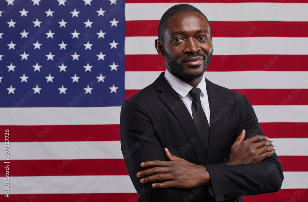 Waist up portrait of confident African-American politician looking at camera while standing with arms crossed against USA flag background, copy space - obrazy, fototapety, plakaty 