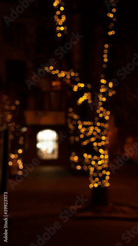 Abstract evening night shimmering bokeh background effect street outside near cafe restaurant. Defocused urban city life blur golden light bulbs garlands. Christmas New Year party holiday concept. 