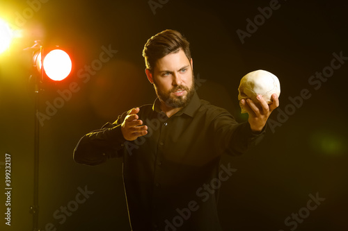 Male actor with human skull on stage