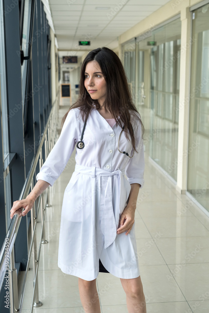 Portrait of female intern healthcare worker standing in modern hospital corridor Portrait of female intern healthcare worker standing in modern hospital corridor