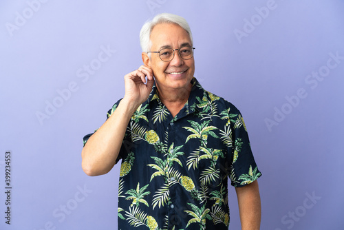 Middle age Brazilian man isolated on purple background laughing