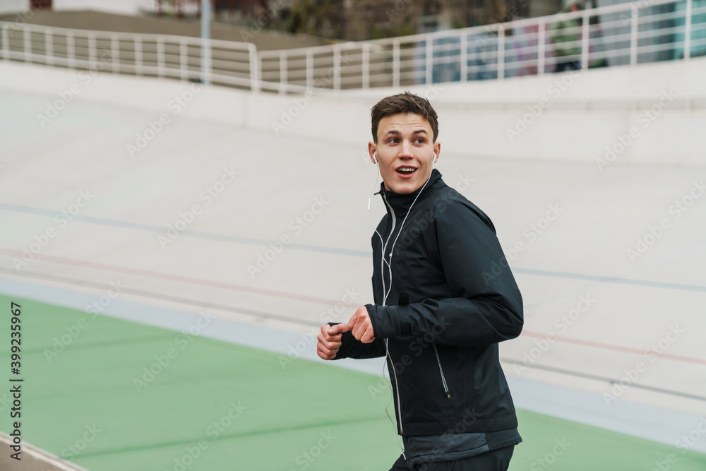 Young sporty man running at the stadium