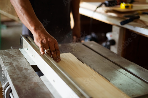 A man cuts wood on a circular saw in a carpenter workshop.