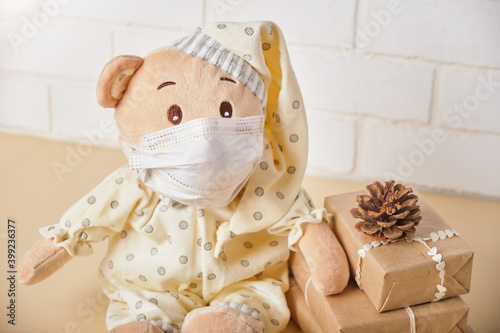 cute teddy bear in face mask, christmas gift boxes, brick white wall background