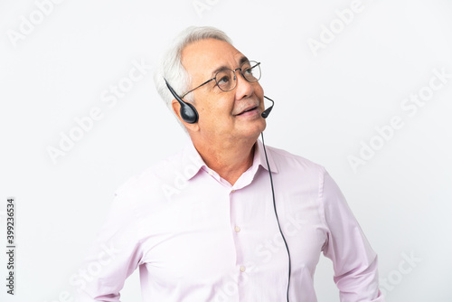 Telemarketer Middle age man working with a headset isolated on white background thinking an idea while looking up © luismolinero