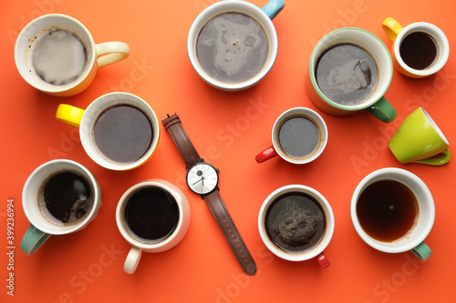 Wrist watch with coffee cups on color background