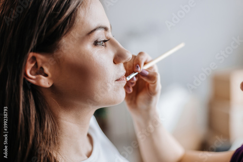 makeup artist applies lip gloss at a beauty salon.