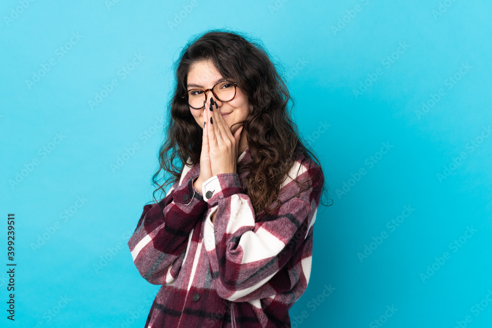 Teenager Russian girl isolated on blue background keeps palm together. Person asks for something Teenager Russian girl isolated on blue background keeps palm together. Person asks for something