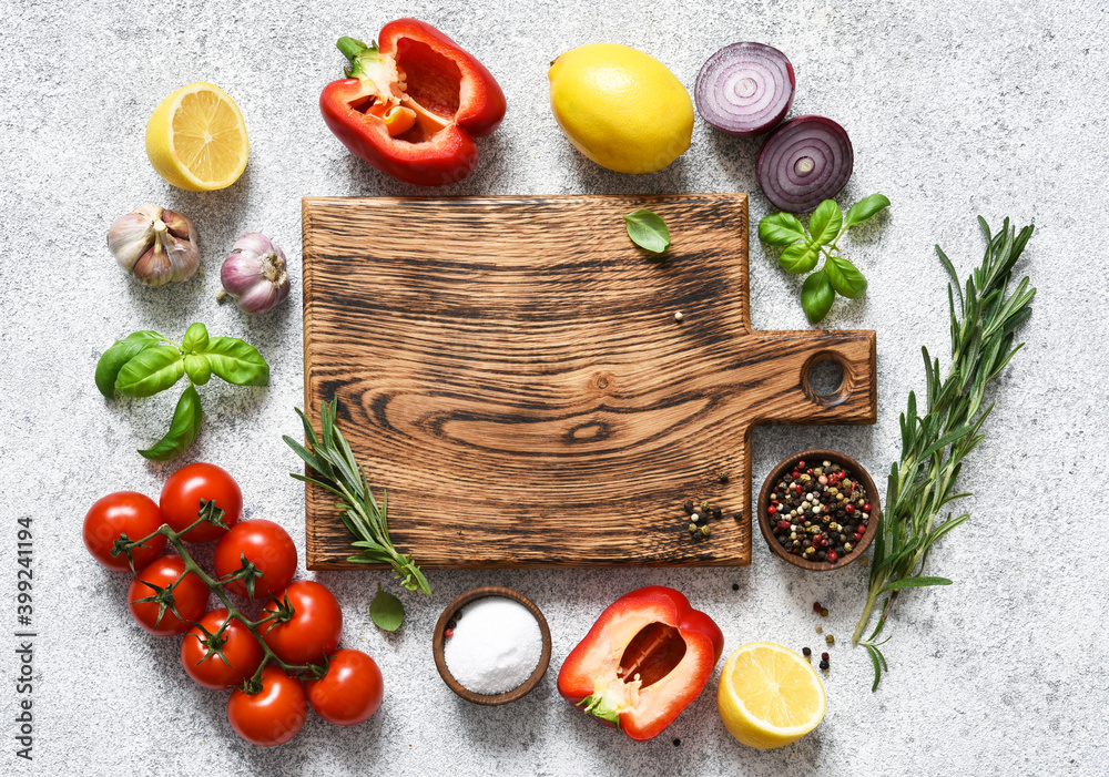 Brown cutting board with spices and vegetables on a light, a concrete kitchen table. Layout. Brown cutting board with spices and vegetables on a light, a concrete kitchen table. Layout.