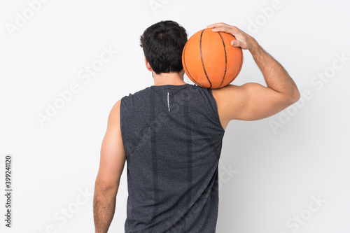 Young handsome man with beard over isolated white background playing basketball in back position
