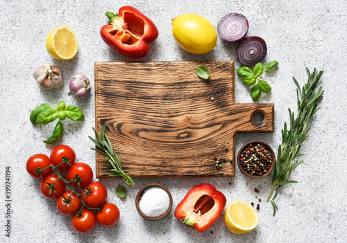 Brown cutting board with spices and vegetables on a light, a concrete kitchen table. Layout.