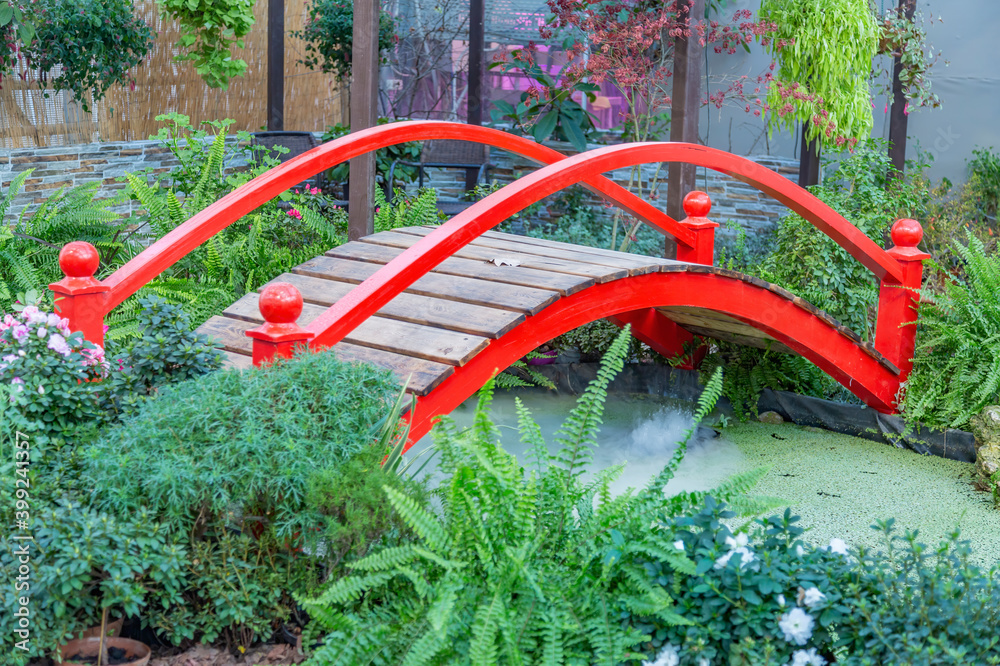 Small red wooden bridge and a pond. Garden or backyard decorating idea