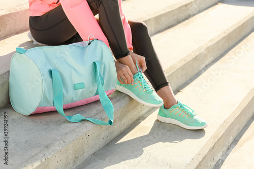 Fototapeta Naklejka Na Ścianę i Meble -  Sporty young woman tying shoelaces outdoors