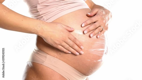 Wallpaper Mural a young pregnant woman applies lotion to her belly on a white background Torontodigital.ca