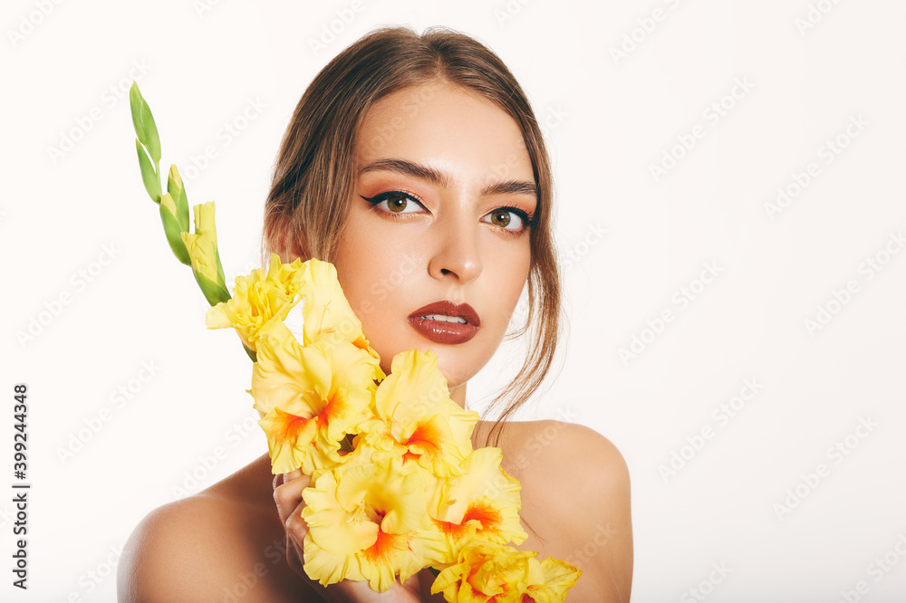Close up portrait of beautiful young woman on white background, studio shot, holding yellow gladiolus flower