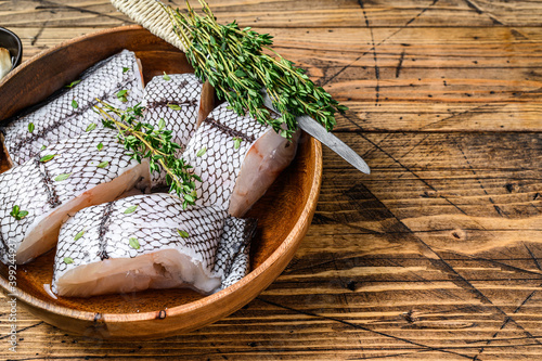 Cut Raw grenadier macrurus white fish without head in a wooden plate. Wooden background. Top view. Copy space photo