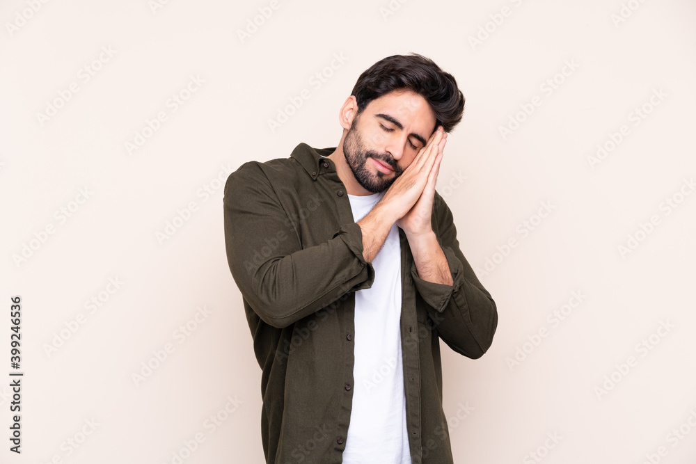 Young handsome man with beard over isolated background making sleep gesture in dorable expression Young handsome man with beard over isolated background making sleep gesture in dorable expression