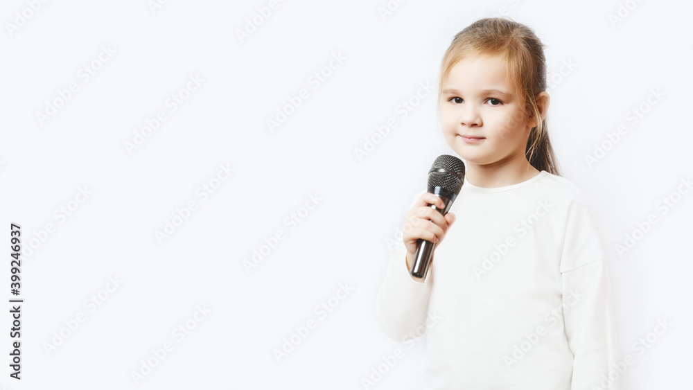 A little adorable caucasian girl holding a microphone in her hands on white background. copy space. A little adorable caucasian girl holding a microphone in her hands on white background. copy space.