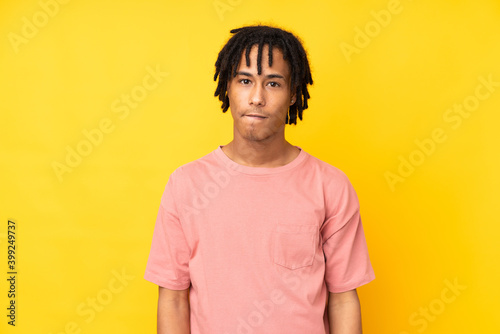 Young african american man isolated on yellow background with confuse face expression
