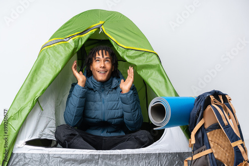 Young african american man inside a camping green tent smiling a lot