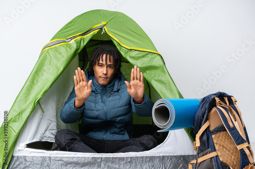 Young african american man inside a camping green tent making stop gesture and disappointed