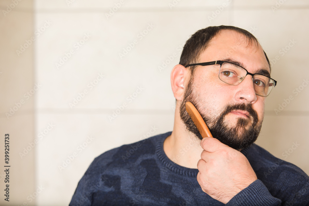 Fototapeta premium Young man comb his beard and moustache and look