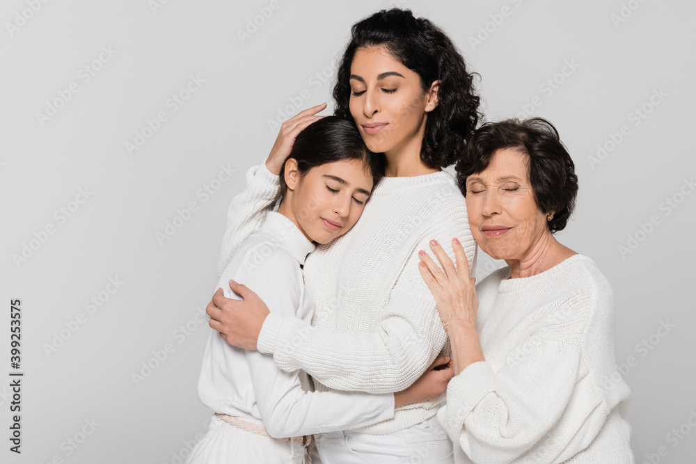 Three generations of hispanic women hugging with closed eyes isolated on grey Three generations of hispanic women hugging with closed eyes isolated on grey