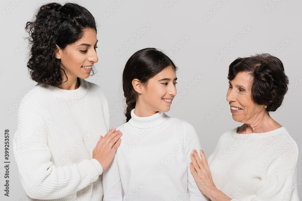 Hispanic mother and granny hugging smiling child isolated on grey, three generations of women Hispanic mother and granny hugging smiling child isolated on grey, three generations of women
