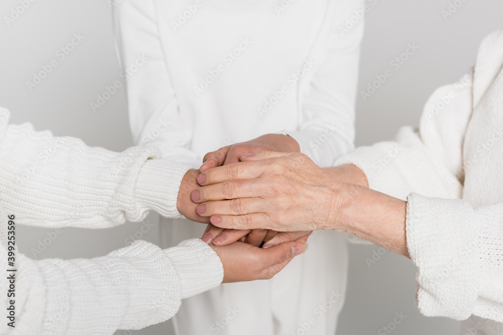 Cropped view of women and child holding hands isolated on grey, three generations of women