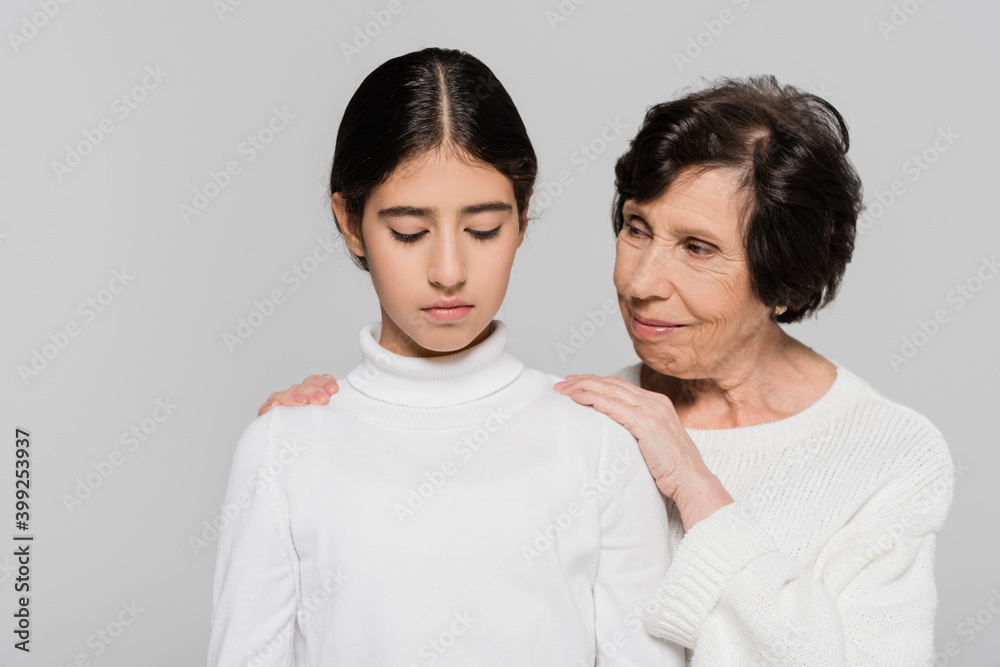 Hispanic grandmother calming upset child isolated on grey, two generations of women Hispanic grandmother calming upset child isolated on grey, two generations of women
