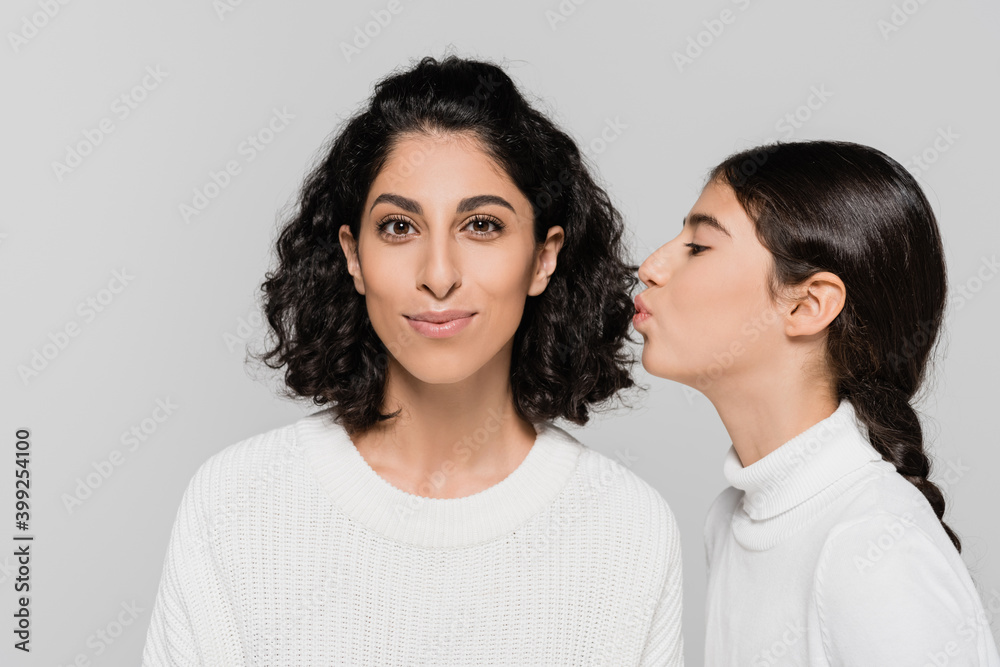 Hispanic kid kissing smiling mother isolated on grey, two generations of women Hispanic kid kissing smiling mother isolated on grey, two generations of women
