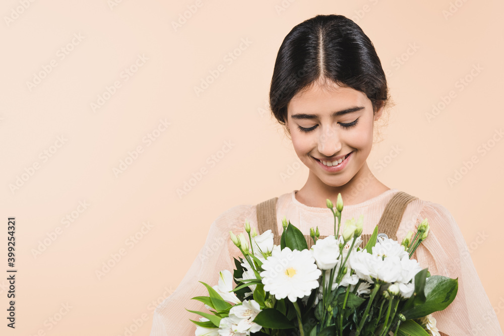 Cheerful hispanic girl looking at flowers isolated on beige Cheerful hispanic girl looking at flowers isolated on beige
