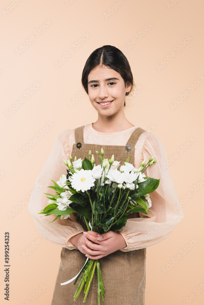Smiling hispanic child holding flowers isolated on beige Smiling hispanic child holding flowers isolated on beige