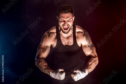 Sportsman muay thai boxer fighting on black background with smoke. Sport concept.