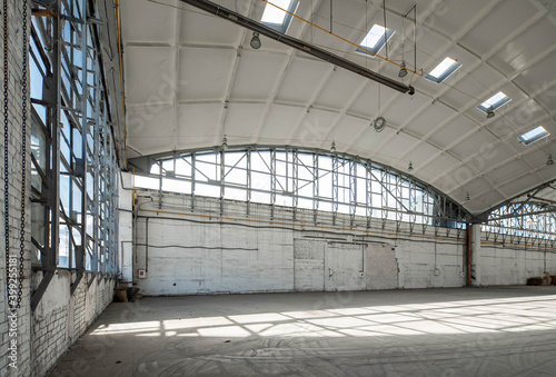 Corner of huge empty industrial warehouse. Modern building hemispherical reinforced concrete load bearing roof. Metal construction.