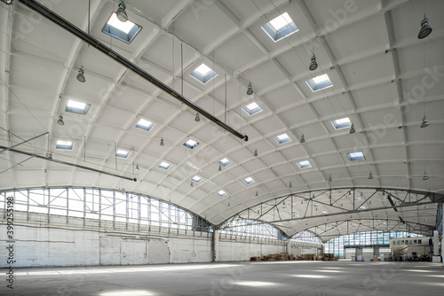 Huge industrial warehouse. White interior. Hemispherical reinforced concrete load bearing roof with windows. Modern architecture. Wooden pallets.