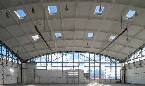 Huge empty industrial warehouse. White interior. Unique architecture. Hemispherical reinforced concrete load bearing roof with windows. Modern building.