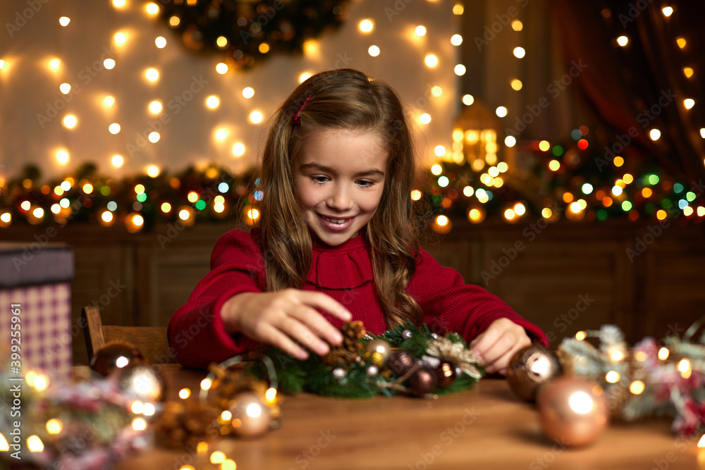 happy cute little child girl decorating Christmas wreath at home.