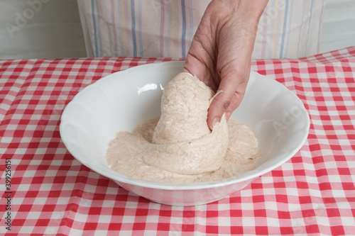 Kneading a dough of bread in a bowl. Female hands working. Making pizza. Cooking at home. Homemade food. Italian cloth.